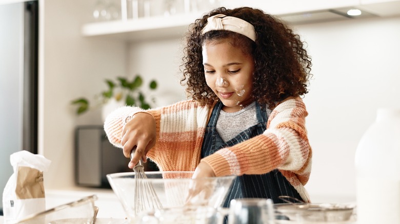 A young girl mixing cookie batter