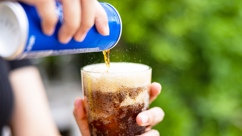 Hand pouring soda into glass