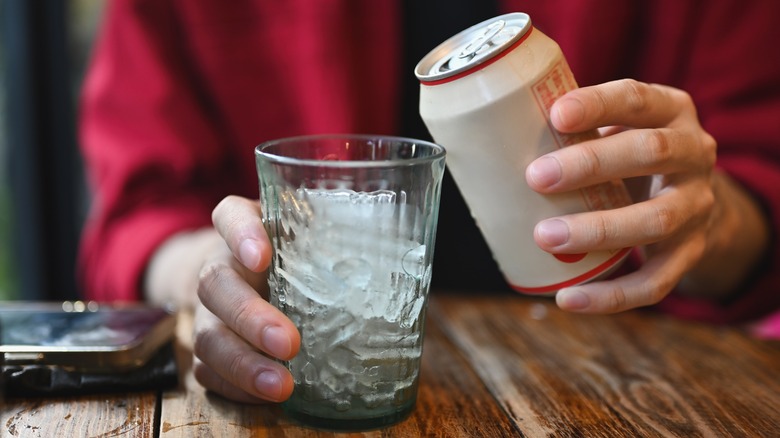 Person holding can and glass