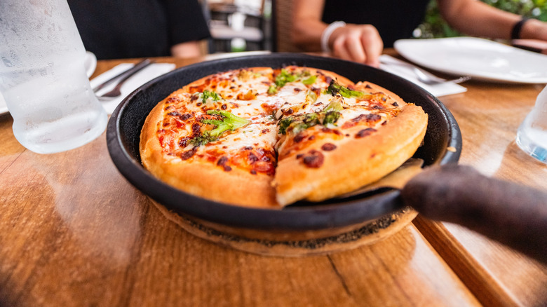 personal pizza in a frying pan on a restaurant table