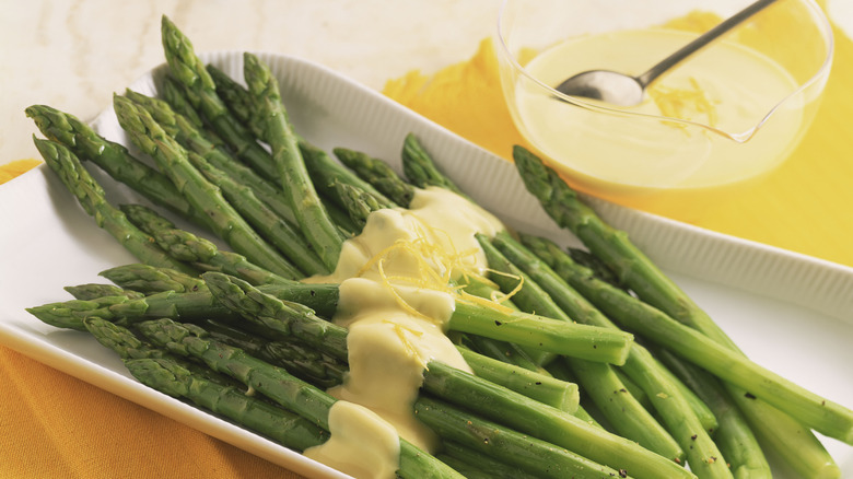 A dish of steamed asparagus topped with a drizzle of hollandaise sauce