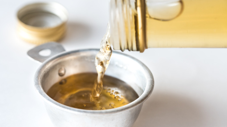 White wine vinegar being poured into a metal measuring cup