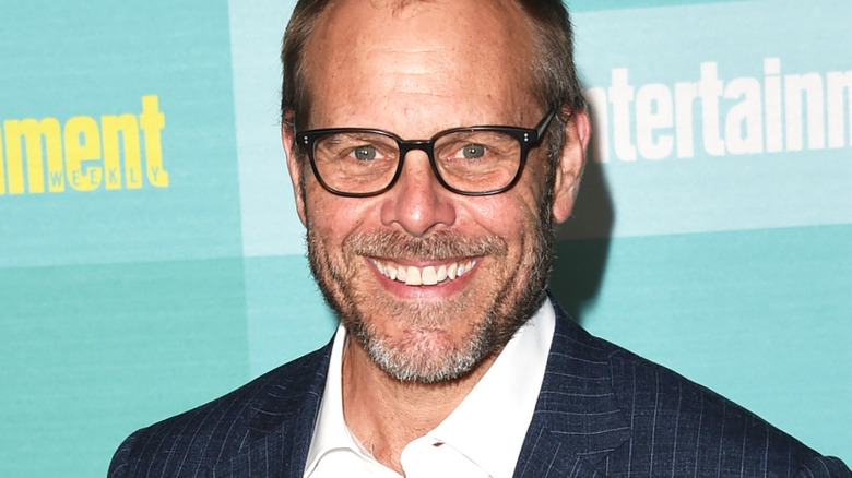 alton brown smiles in striped blazer and white shirt with glasses