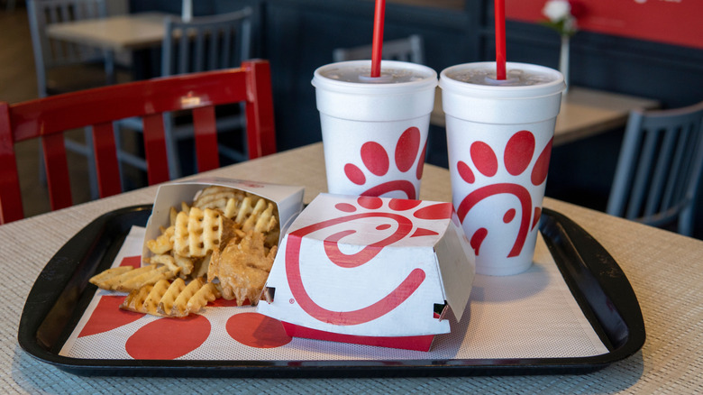 A Chick-fil-A order of fries and two takeaway drinks containers with red straws on a tray