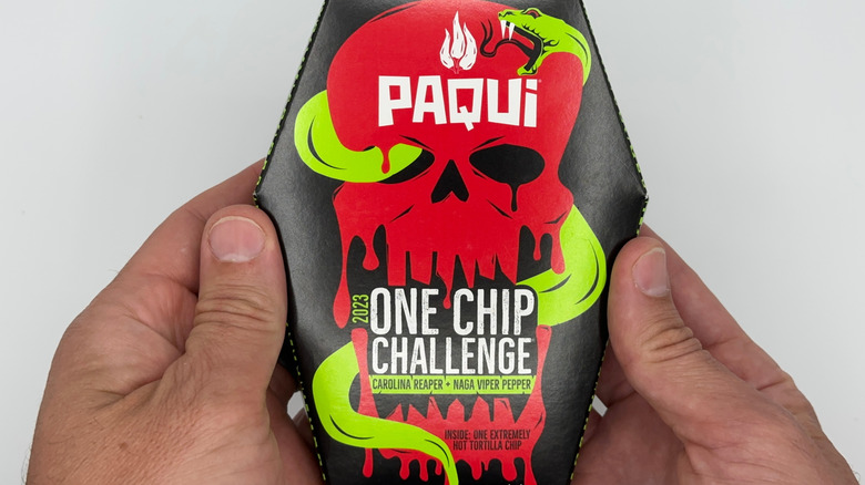 Two hands holding the Paqui 'One Chip Challenge' box.