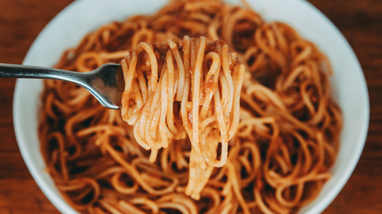 Bowl of spaghetti with tomato sauce, wrapped around a fork