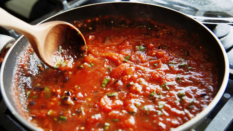 Pasta sauce inside a pan with a wooden spoon