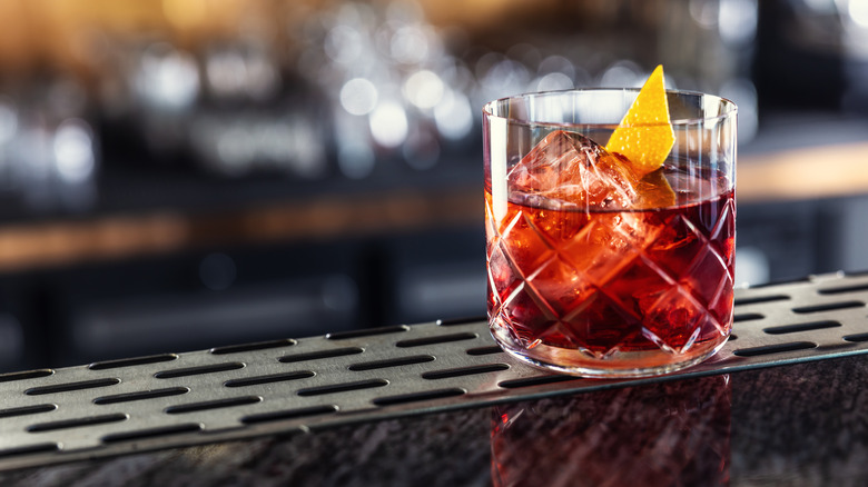 A negroni in a rocks glass sits on a bar