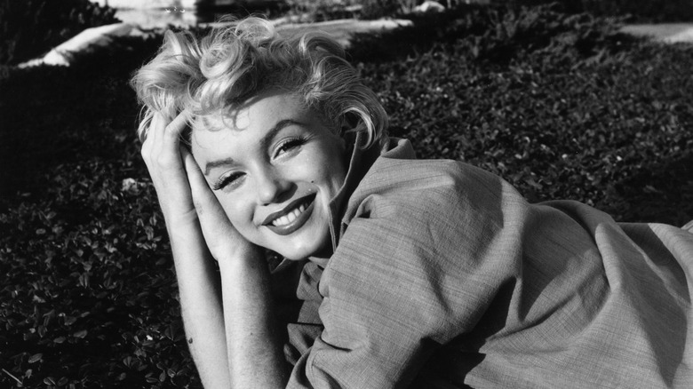 A black and white photo of Marilyn Monroe lying on some grass