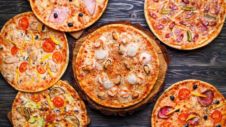 Selection of pizzas with different toppings on a dark wood surface