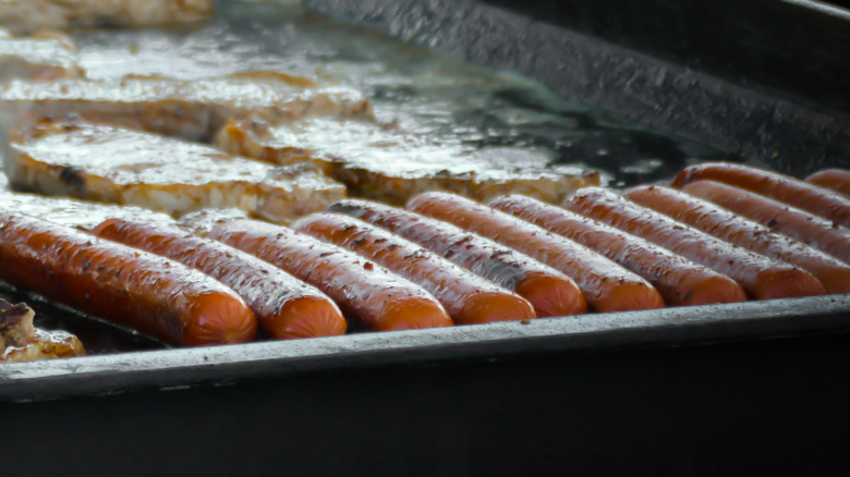 A row of hot dogs cooking on a hot griddle