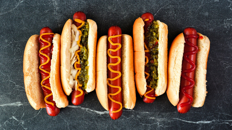 Five hot dogs topped with mustard, ketchup, and relish