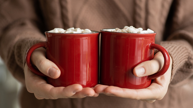 woman's hands two cocoa mugs