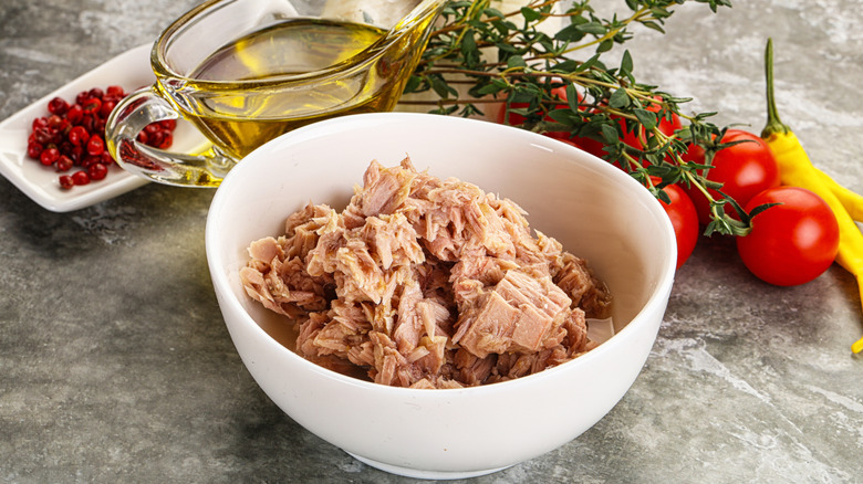 bowl of tuna surrounded by fresh vegetables and herbs to mix in