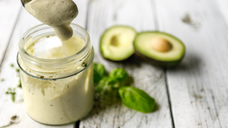 jar of avocado creamy sauce beside avocado halves