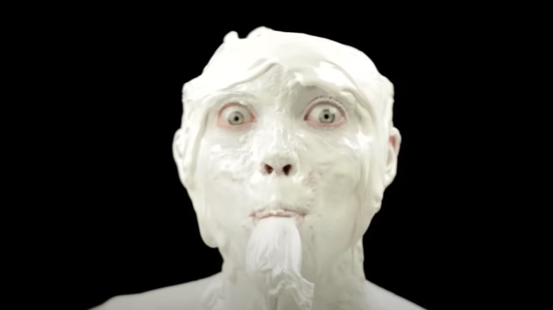 A man covered in ice cream puts a spoon to his mouth