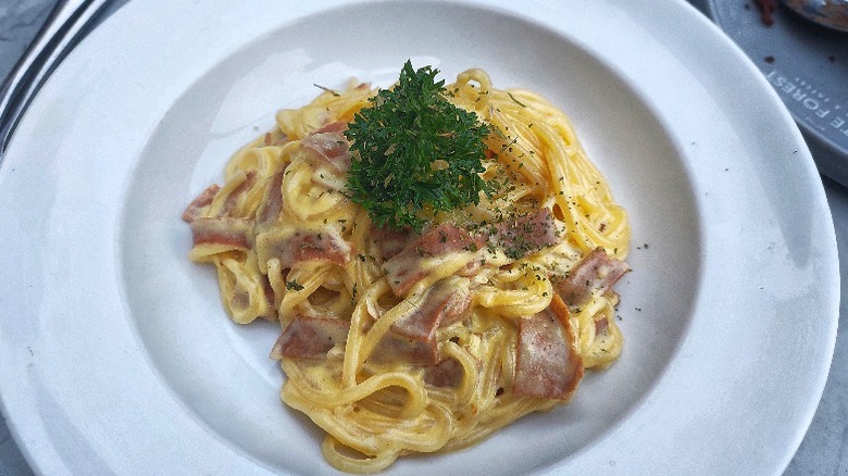 A bowl of spaghetti carbonara with parsley