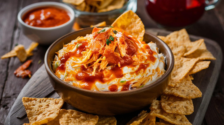 Bowl of buffalo chicken dip with tortilla chips on the side