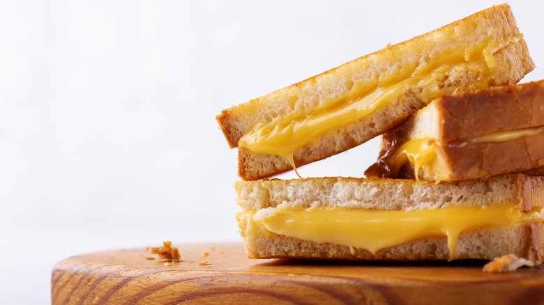 Close up of three grilled cheese sandwiches on a cutting board