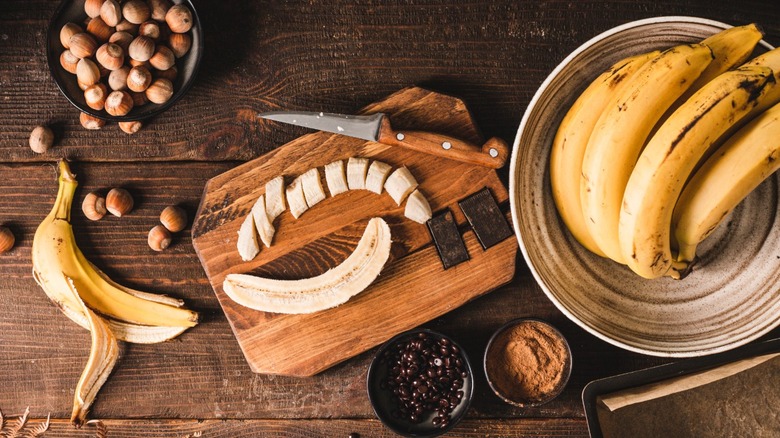 bananas being sliced on cutting board with toppings around