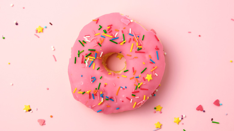 Close up of a pink donut with sprinkles