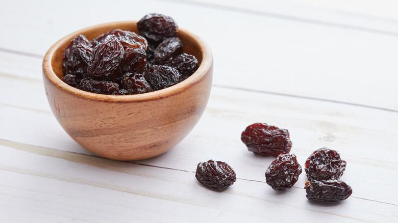 Raisins sitting on a white counter and in a bowl.