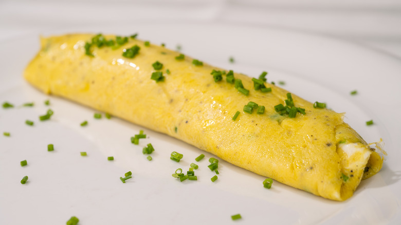 A french omelet on a plate with chives