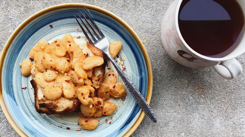 plate of beans on toast with a mug of tea