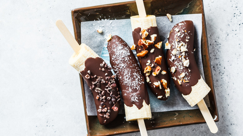 chocolate covered bananas with nuts and other toppings