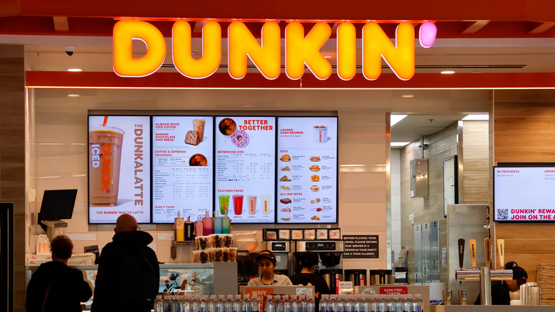 A Dunkin' storefront with people ordering at a register