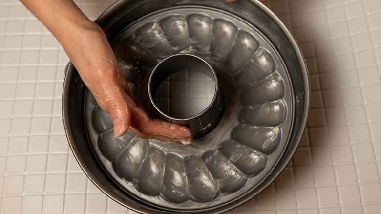 A hand greasing a cake pan