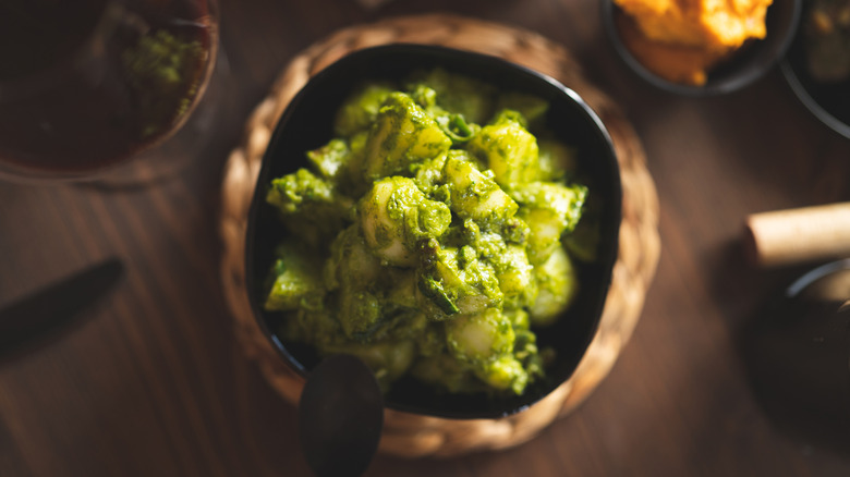 bowl of potato salad with green dressing prepared on dinner table