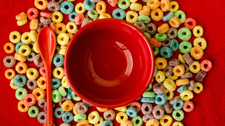 An empty red bowl and spoon with Froot Loops laid out around it