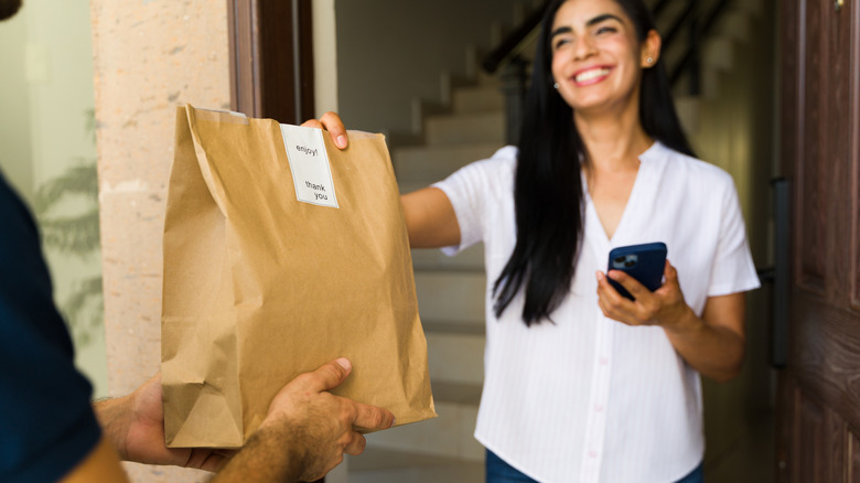 A person receiving a takeout order in a paper bag