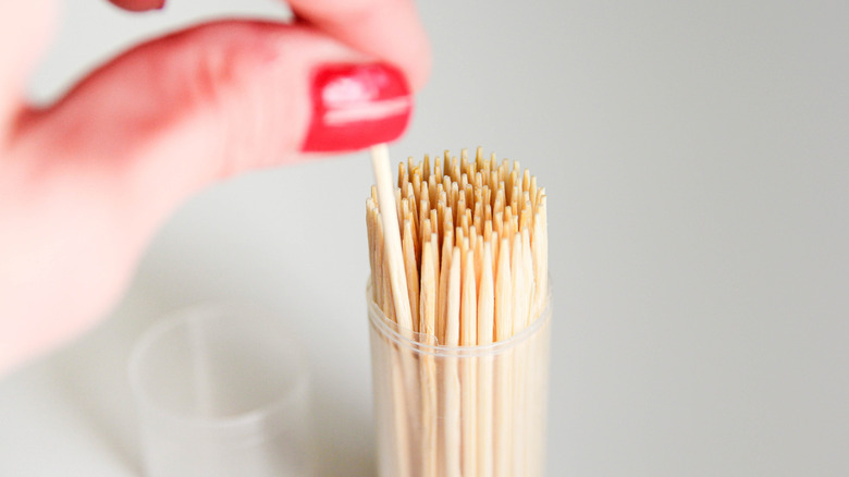 Fingers picking up a toothpick