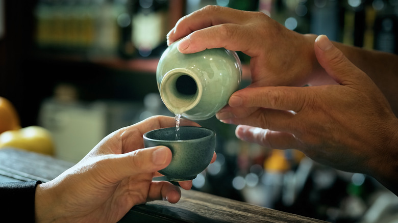 sake being poured with two hands into small cup