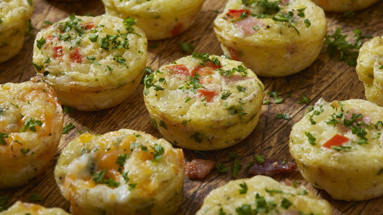 Veggie and bacon egg bites resting on a wooden platter