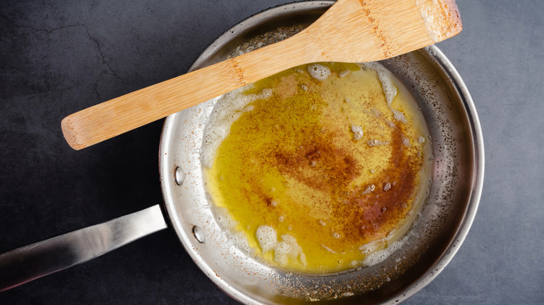 Stainless steel pan with browned butter and wood spatula