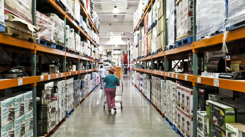 Shopper wheels a cart down a Costco warehouse aisle