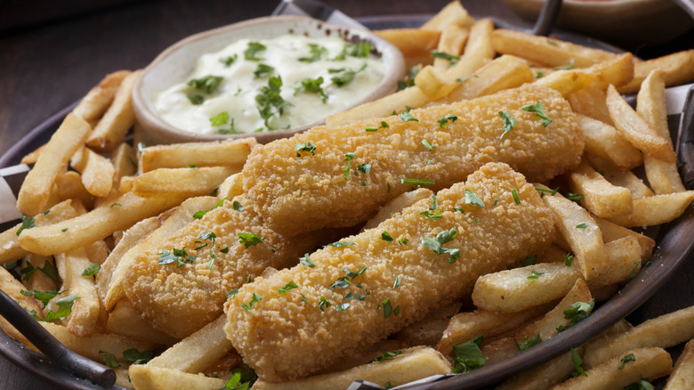 A plate of fries and fish sticks with tartar sauce