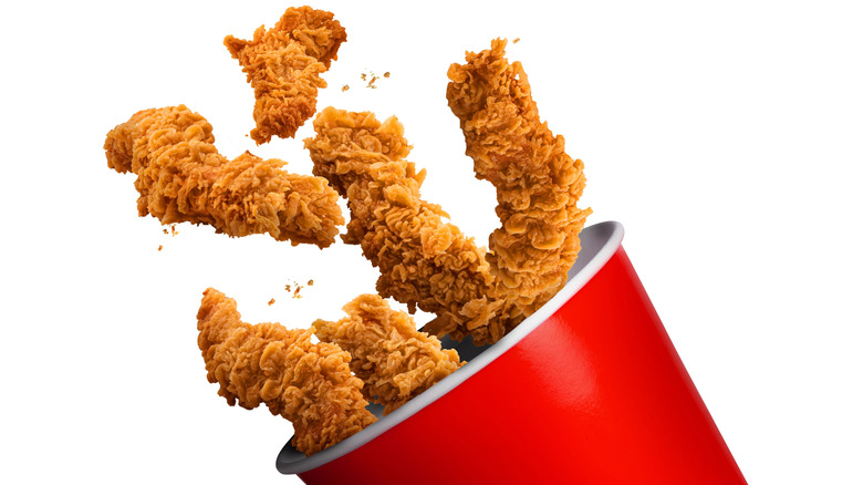 Fried Chicken hot crispy strips crunchy pieces of tenders in a Bucket - large Red box isolated in white background