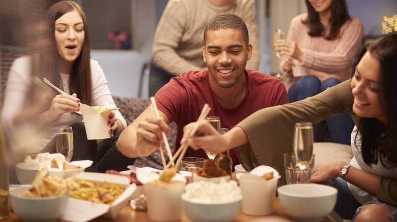 Friends sitting around eating Chinese takeout.