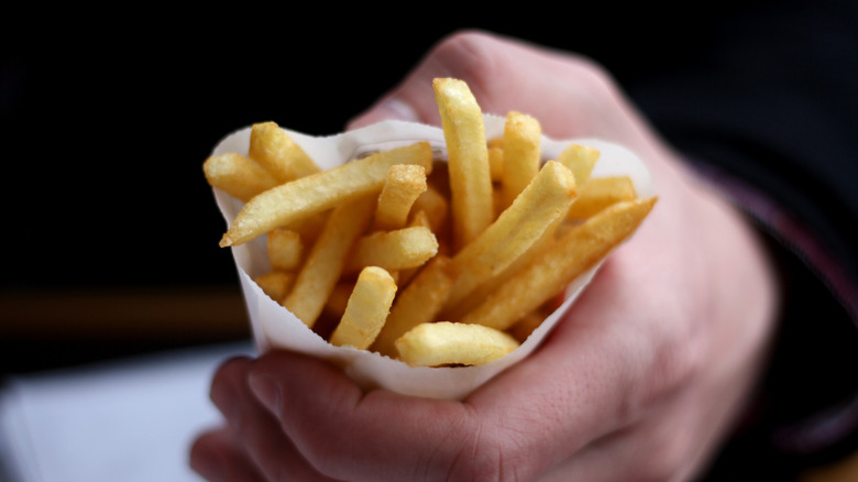 A person holding a portion of french fries.