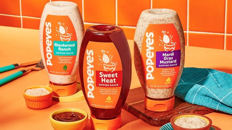 Popeyes dipping sauces bottles with small bowls of each flavor