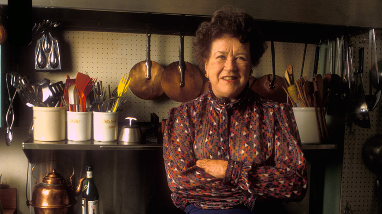 Julia Child in front of various utensils and cookware