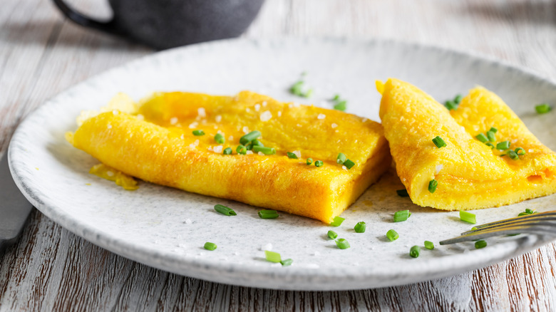 French omelet on white plate with salt and chives