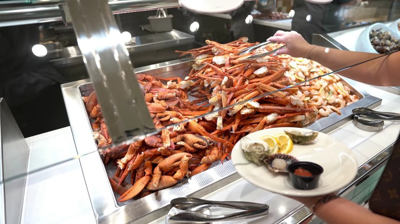 A person helping themselves to crab legs at the Bacchanal Buffet.