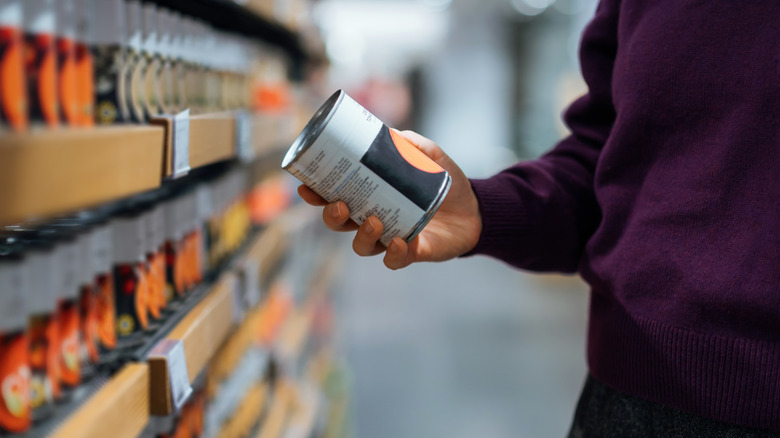 Shopper examines canned item at the grocery store