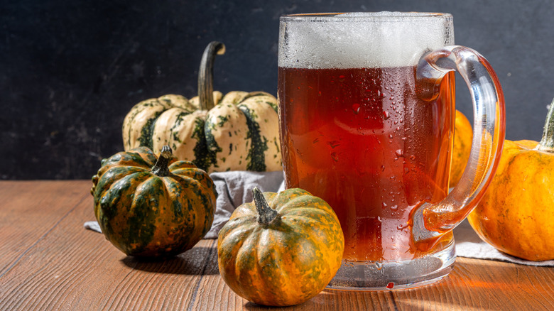 A pumpkin ale next to gourds