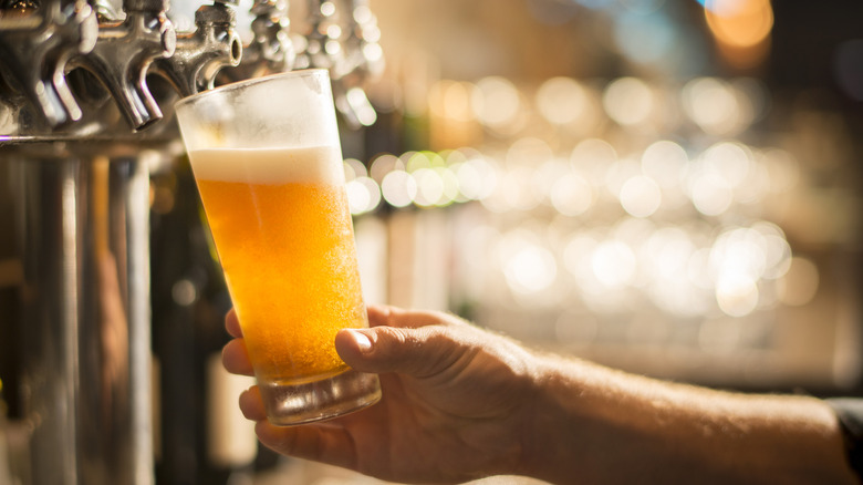 Bartending pouring a foamy beer